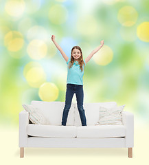 Image showing smiling little girl jumping on sofa