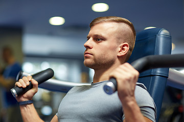 Image showing man exercising and flexing muscles on gym machine