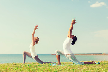 Image showing smiling couple making yoga exercises outdoors