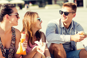 Image showing group of smiling friends sitting on city square