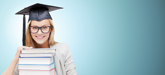 Image showing happy student in mortar board cap with books