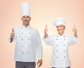 Image showing happy chefs or cooks couple showing thumbs up