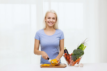 Image showing smiling young woman chopping vegetables at home