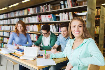 Image showing happy student girl writing to notebook in library