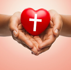 Image showing close up of hands holding heart with cross symbol