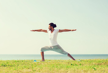 Image showing smiling man making yoga exercises outdoors