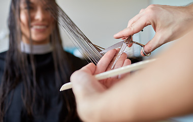 Image showing happy woman with stylist cutting hair at salon