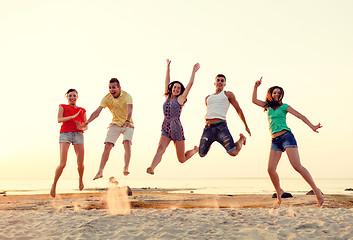 Image showing smiling friends dancing and jumping on beach