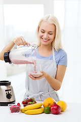 Image showing smiling woman with blender preparing shake at home