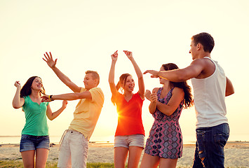 Image showing smiling friends dancing on summer beach