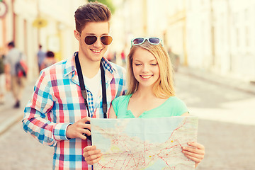 Image showing smiling couple with map and photo camera in city