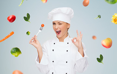 Image showing smiling female chef with fork and tomato