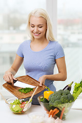 Image showing smiling woman cooking vegetable salad at home