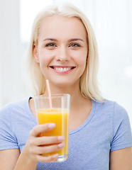 Image showing smiling woman drinking orange juice at home