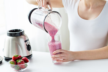 Image showing close up of woman with blender pouring milk shake