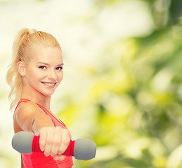 Image showing smiling beautiful sporty woman with dumbbell