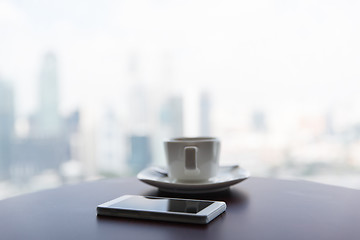 Image showing close up of smartphone and coffee cup on table