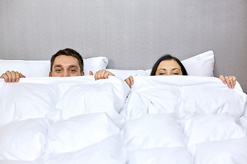 Image showing happy couple hiding under blanket in bed