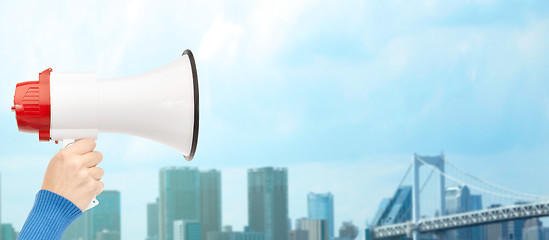 Image showing woman hand holding megaphone over city background