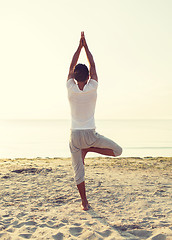 Image showing man making yoga exercises outdoors from back