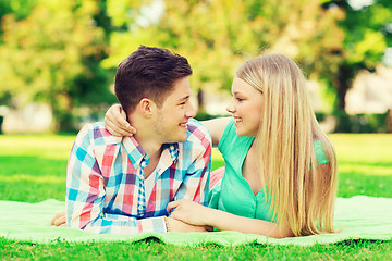 Image showing smiling couple lying on blanket in park