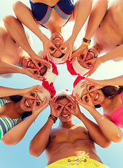 Image showing smiling friends in circle on summer beach