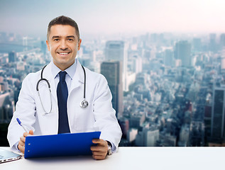 Image showing happy doctor with clipboard over city background