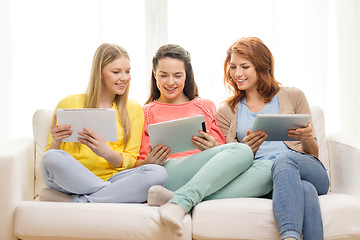 Image showing three smiling teenage girls with tablet pc at home