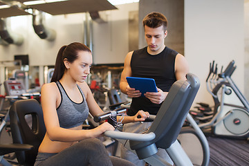 Image showing woman with trainer on exercise bike in gym