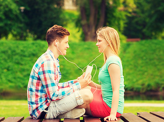 Image showing smiling couple with smartphone and earphones