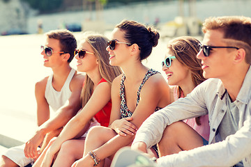 Image showing group of smiling friends sitting on city square