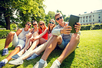 Image showing smiling friends with tablet pc computer in park