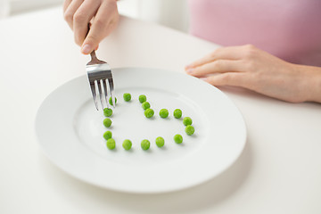 Image showing close up of woman with fork eating peas