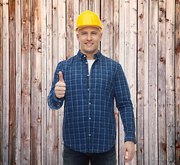 Image showing smiling male builder in helmet showing thumbs up