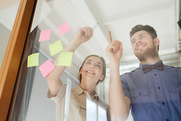 Image showing happy creative team writing on blank office glass