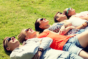 Image showing group of smiling friends lying on grass outdoors