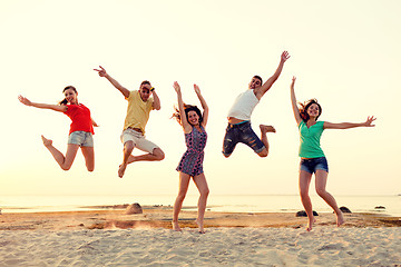 Image showing smiling friends dancing and jumping on beach