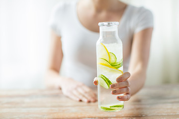 Image showing close up of woman with fruit water in glass bottle