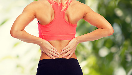 Image showing close up of sporty woman touching her back