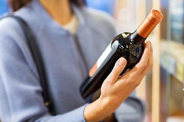 Image showing happy woman choosing and buying wine in market