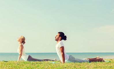 Image showing smiling couple making yoga exercises outdoors