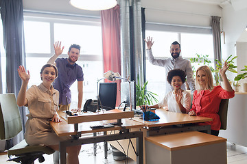 Image showing happy creative team waving hands in office