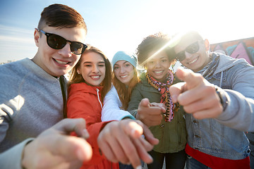 Image showing happy teenage friends pointing fingers on street