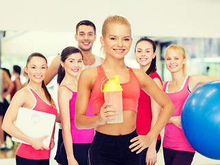 Image showing smiling sporty woman with protein shake bottle