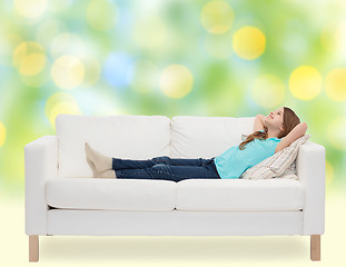 Image showing smiling little girl lying on sofa and dreaming