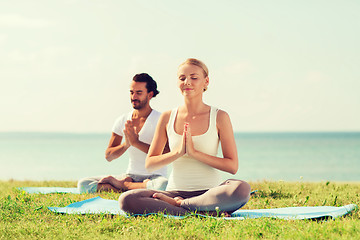 Image showing smiling couple making yoga exercises outdoors