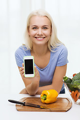 Image showing smiling woman with smartphone cooking vegetables