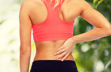 Image showing close up of sporty woman touching her back