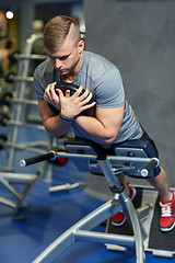 Image showing young man flexing back muscles on bench in gym