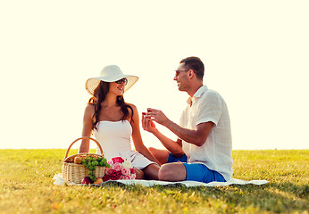 Image showing smiling couple with small red gift box on picnic